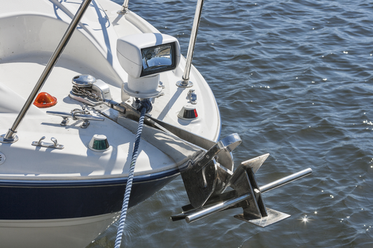 Front bow nose of a boat with a mounted stainless steel anchor ready to be dropped in the water